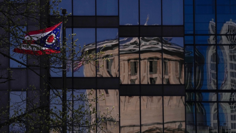 The Ohio Statehouse cupola is seen reflected in a building across the street as the Ohio burgee, the flag of the state of Ohio, flies in Columbus, Ohio, April 15, 2024. (AP Photo/Carolyn Kaster)