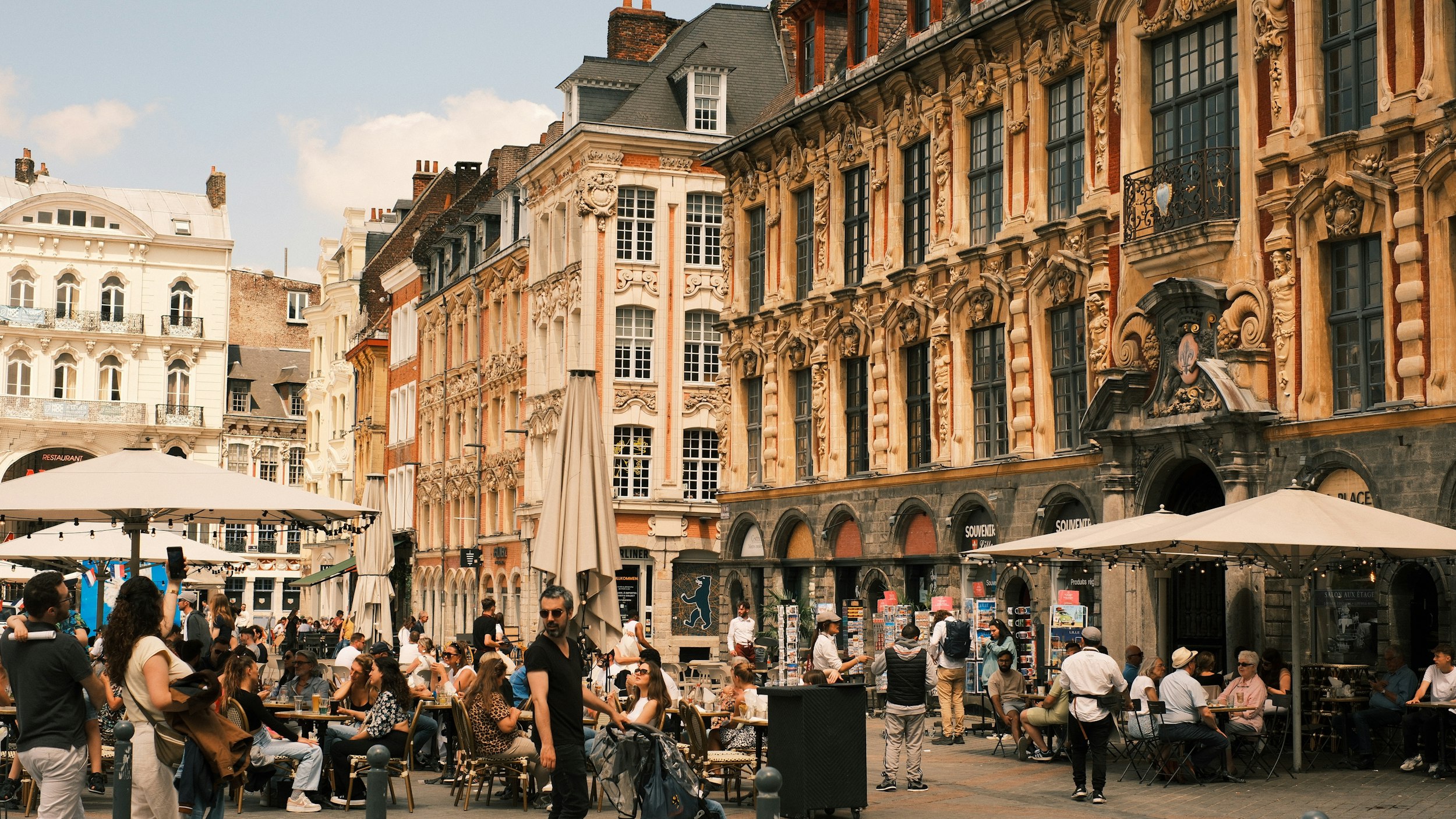 A group of people sitting at tables in front of buildings