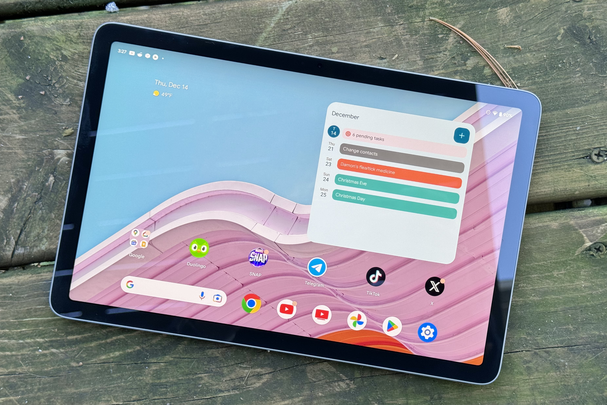 La tableta Google Pixel sentada afuera con la pantalla encendida.