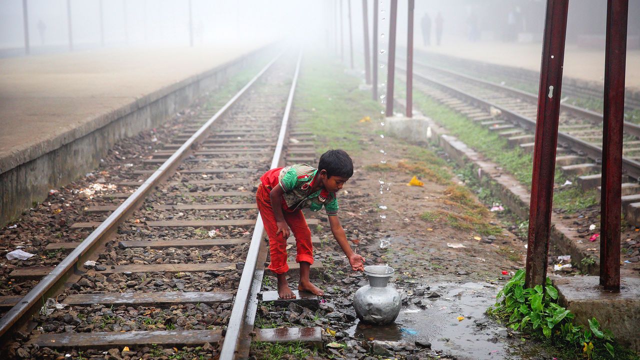 A child collects water from a station pipe that supplies water in Bangladesh