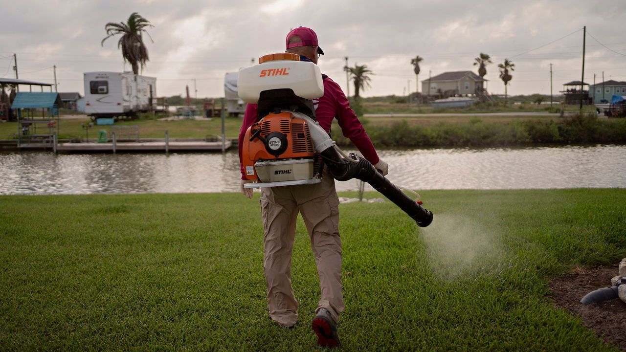 A worker from the Mosquito Authority treats the grounds of a home in Sargent, Texas.