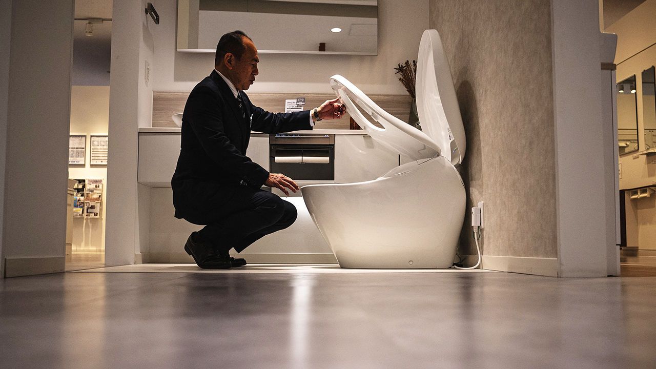 A man looks at the washlet functions of a TOTO toilet.