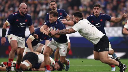 Le de mi de mêlée du Xv de France Antoine Dupont tente d'échapper au Néo-Zélandais Tyrel Lomax, lors du match entre la France et la Nouvelle-Zélande, le 16 novembre 2024 au Stade de France. (ANNE-CHRISTINE POUJOULAT / AFP)