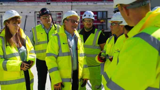 Group of men and a woman talking to each other in hi-viz jackets and hard hats