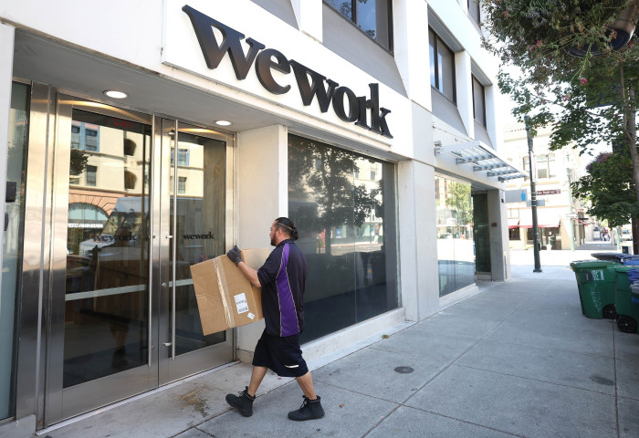 A man delivers a cardboard box to a WeWork office