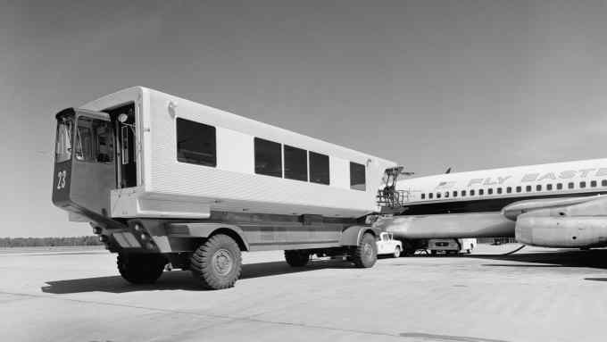 A bus-like vehicle parked at the open door of a jumbo jet