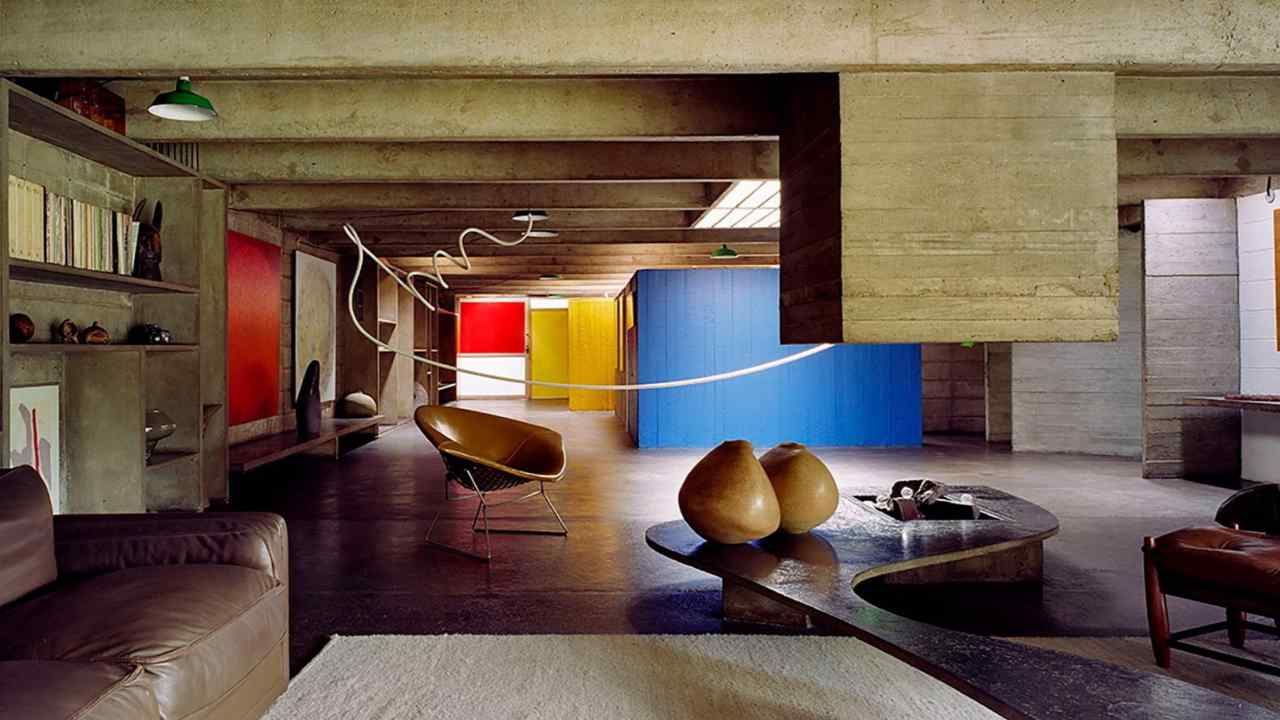 brutalist concrete open space with stone sculptures, leather sofas and bright blue, yellow and red walls