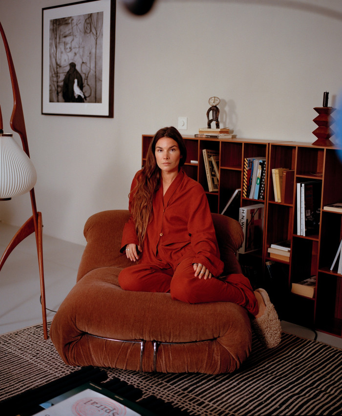 Kuiper on an armchair in her studio; on the wall is a photograph by Roger Ballen