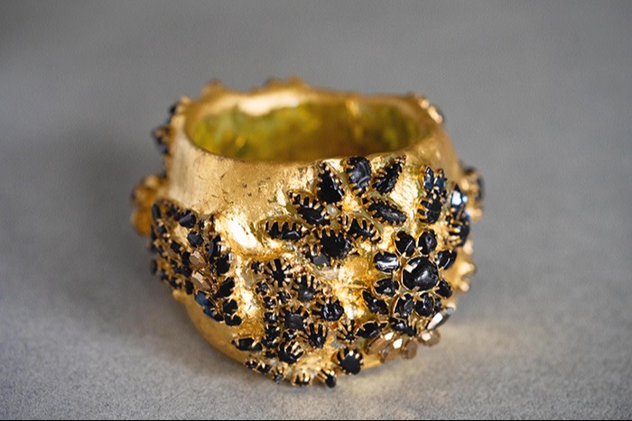 a cuff made from acrylic covered in gold leaf, set with historic costume jewellery findings, rhinestones and obsidian