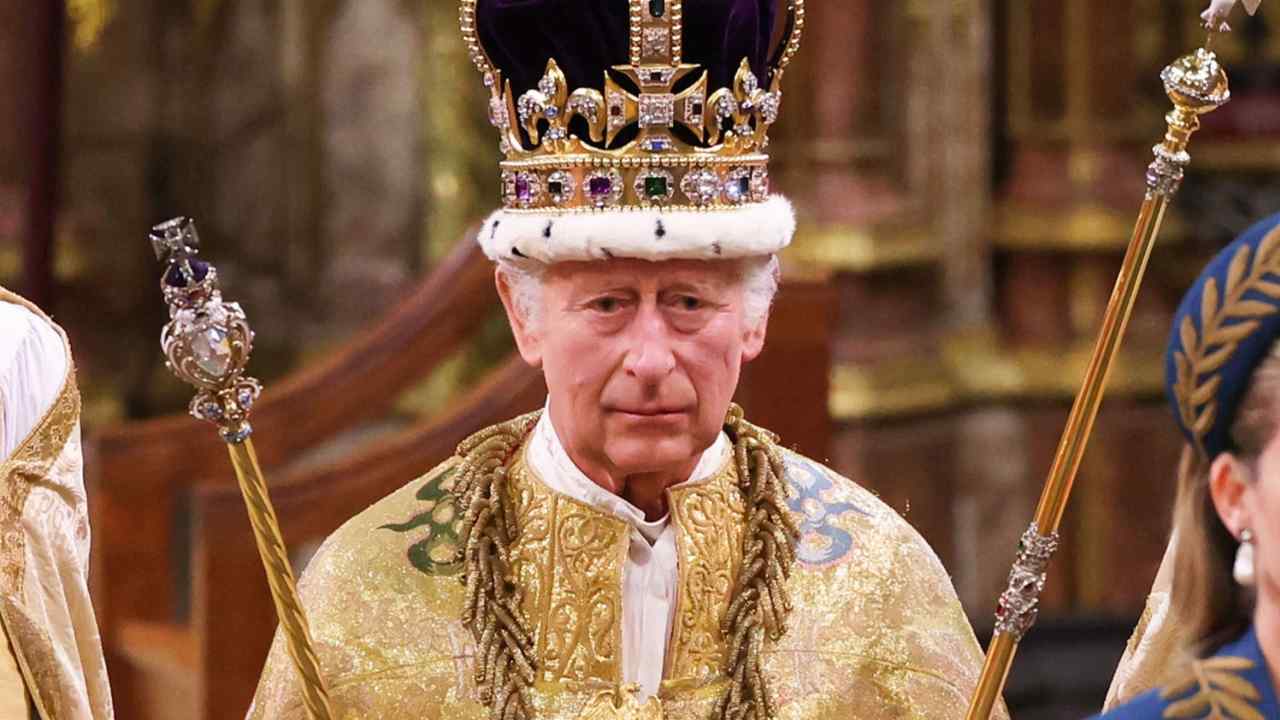 King Charles, wearing a crown and a golden robe and vest. In each hand is a sceptre