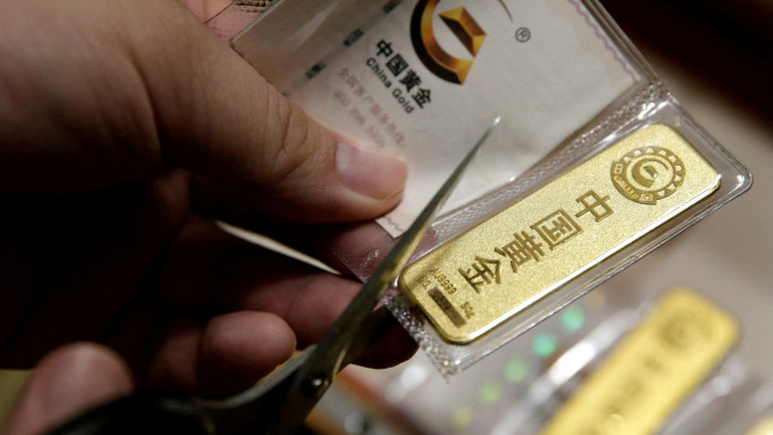 A man cuts open a bag of gold bars