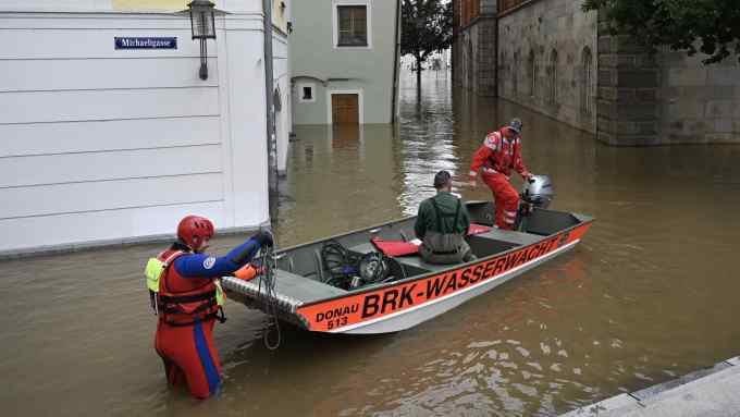 A water rescue helper stands in the water next to his team sitting in their boat on the flooded streets in the center of Passau in Bavaria, southern Germany