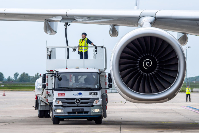 An aircraft on the ground is being filled with sustainable aviation fuel