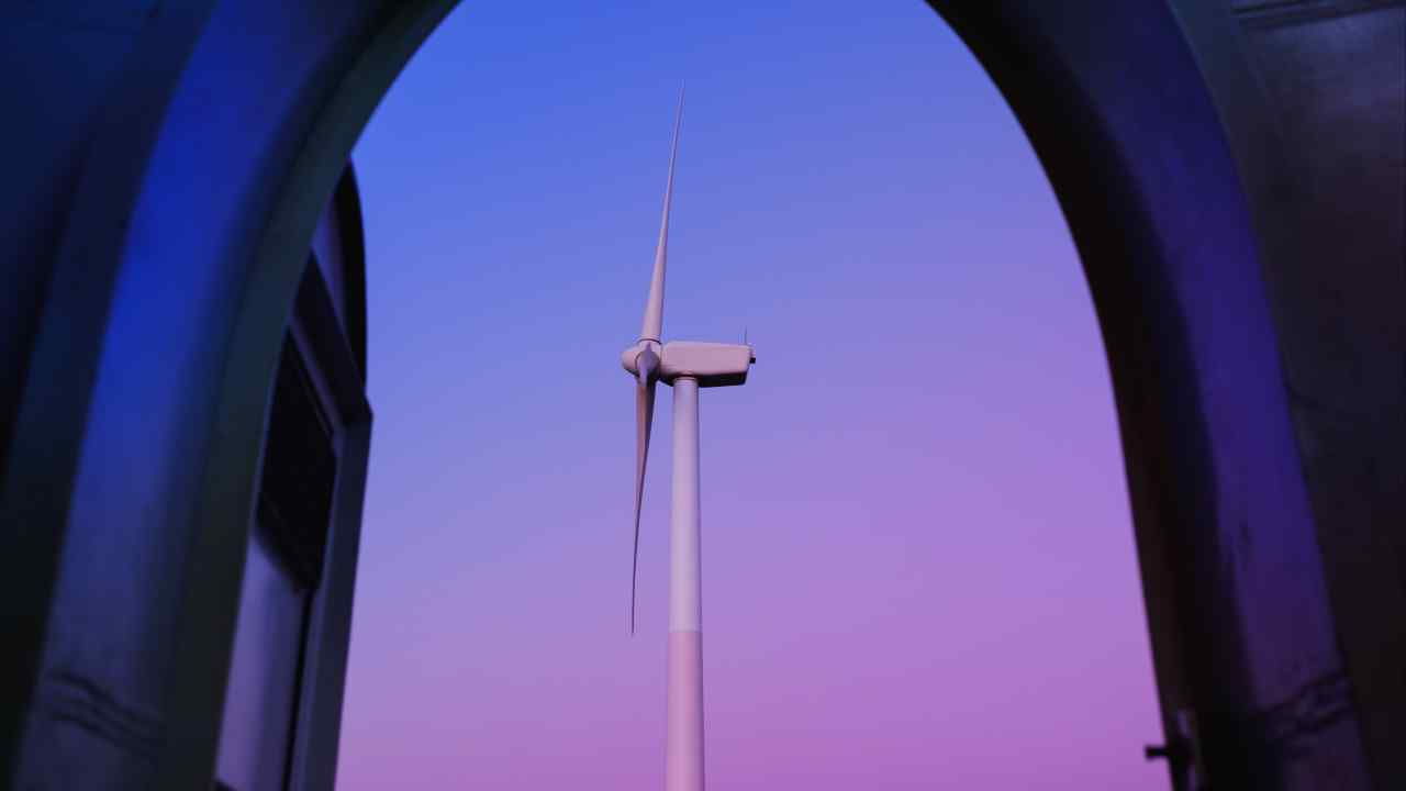 A wind turbine stands tall against a backdrop of a vibrant purple and blue sky, framed by an arched structure