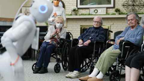 A robot moves and speaks to elderly residents in a room