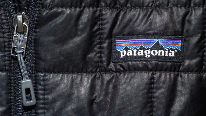 Close-up of a black fabric texture on a Patagonia jacket with a detailed view of a zipper and the brand’s logo patch which features a colorful mountain range design