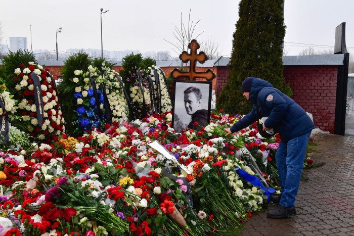 A mourner lays flowers on the grave of Russian opposition leader Alexei Navalny at the Borisovo cemetery in Moscow