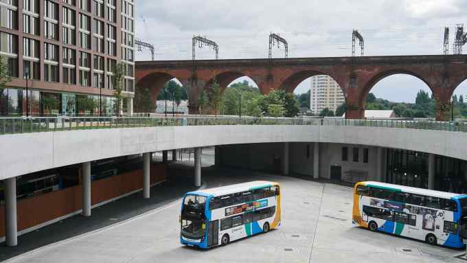 Two double-decker buses appear on a concrete forecourt before a viaduct