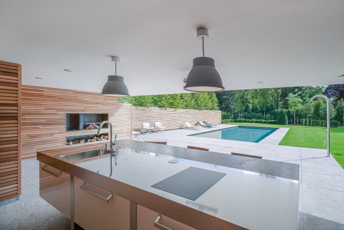 The view from an outdoor covered kitchen towards a swimming pool 
