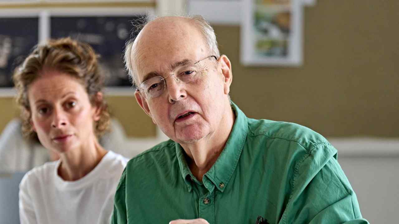 A man wearing a green shirt and glasses next to a woman in a white T-shirt