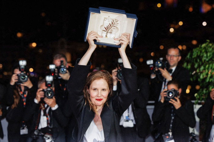 A woman holding up a box containing the Palme d’Or award