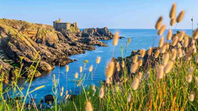 A view over a craggy coast, with an old fortress perched on the cliff