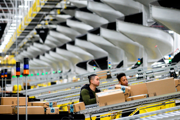 Workers watch packages on a conveyor belt at an Amazon warehouse