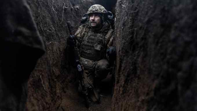 A Ukrainian soldier crouches in a trench