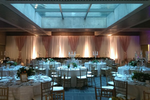 Formal dinner tables with light filtering through the glass floor above, and curtains along the far wall. 