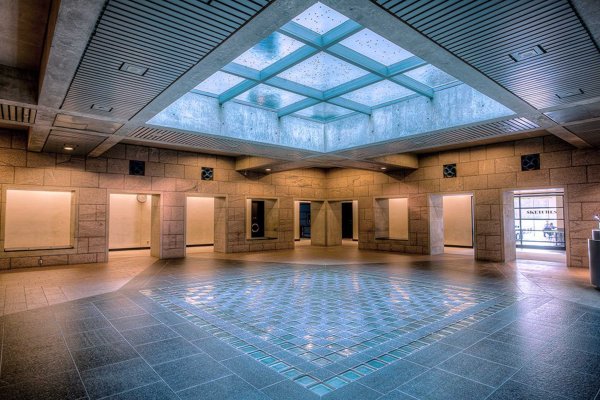 Large open space with blue light filtering through a glass-bottomed pool on the floor above. 