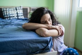 A worried woman sitting next to their bed