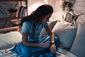 A woman sets her smartwatch to monitor sleeping patterns.