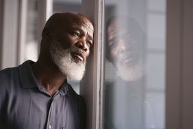 Man looking out the window, reflection of his face in the window