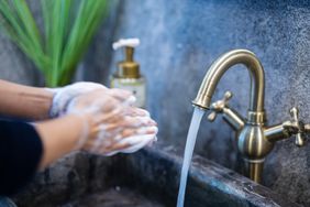 person with mysophobia washing germs off hands with soap and a running faucet in the background