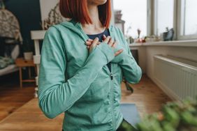 Woman with hands on chest doing breathing exercise at home