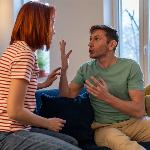 A couple yelling at each other while sitting on a couch.