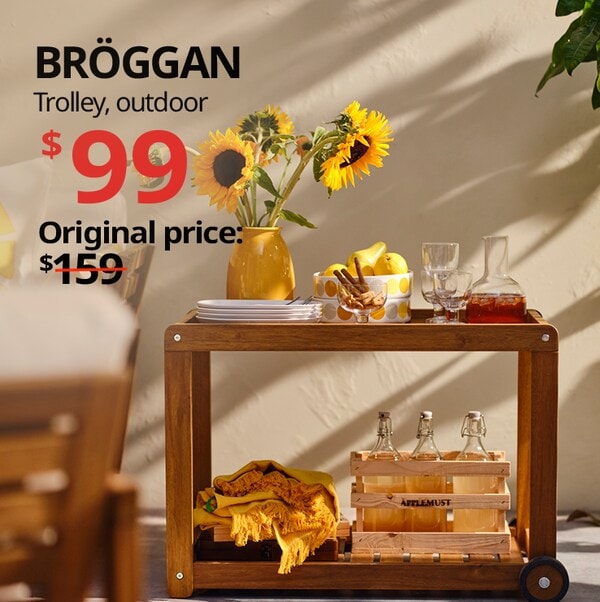 BROGGAN outdoor trolley with plates, a carafe with icedtea and cups on top of it and a yellow flower pot with sunflowers. Text reads "BROGGAN trolley, outdoor, $99, usual price: $159 with a slash. 