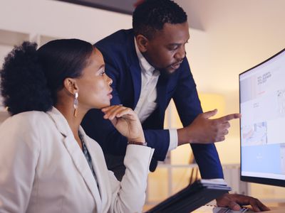 A business professional explaining something on a monitor to another person.