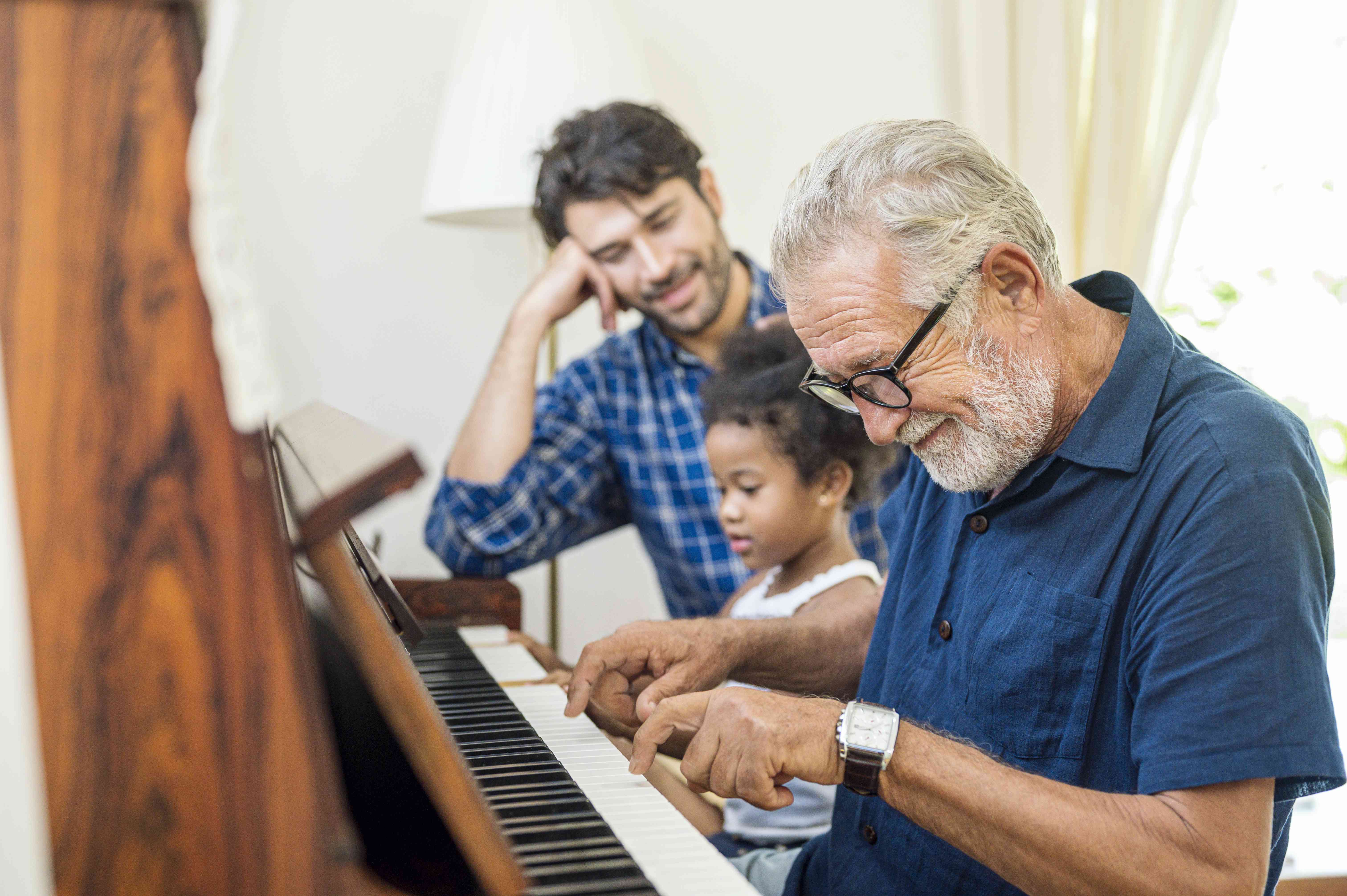 Three generations of family members gather around a piano.