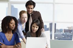 Business people in an office looking at a laptop