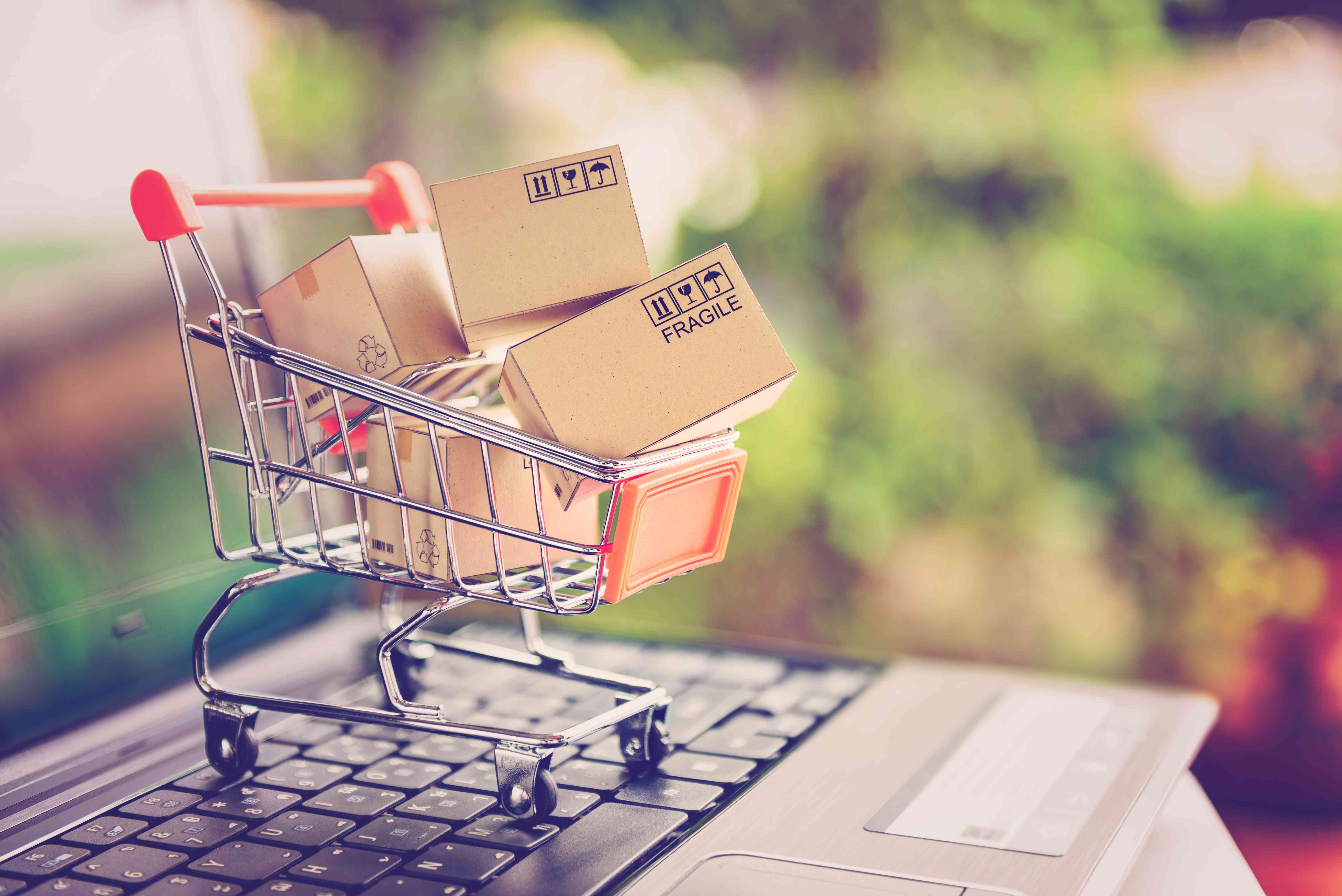 Online shopping and delivery service concept. Paper cartons in a shopping cart on a laptop keyboard, this image implies online shopping that customer order things from retailer sites via the internet.