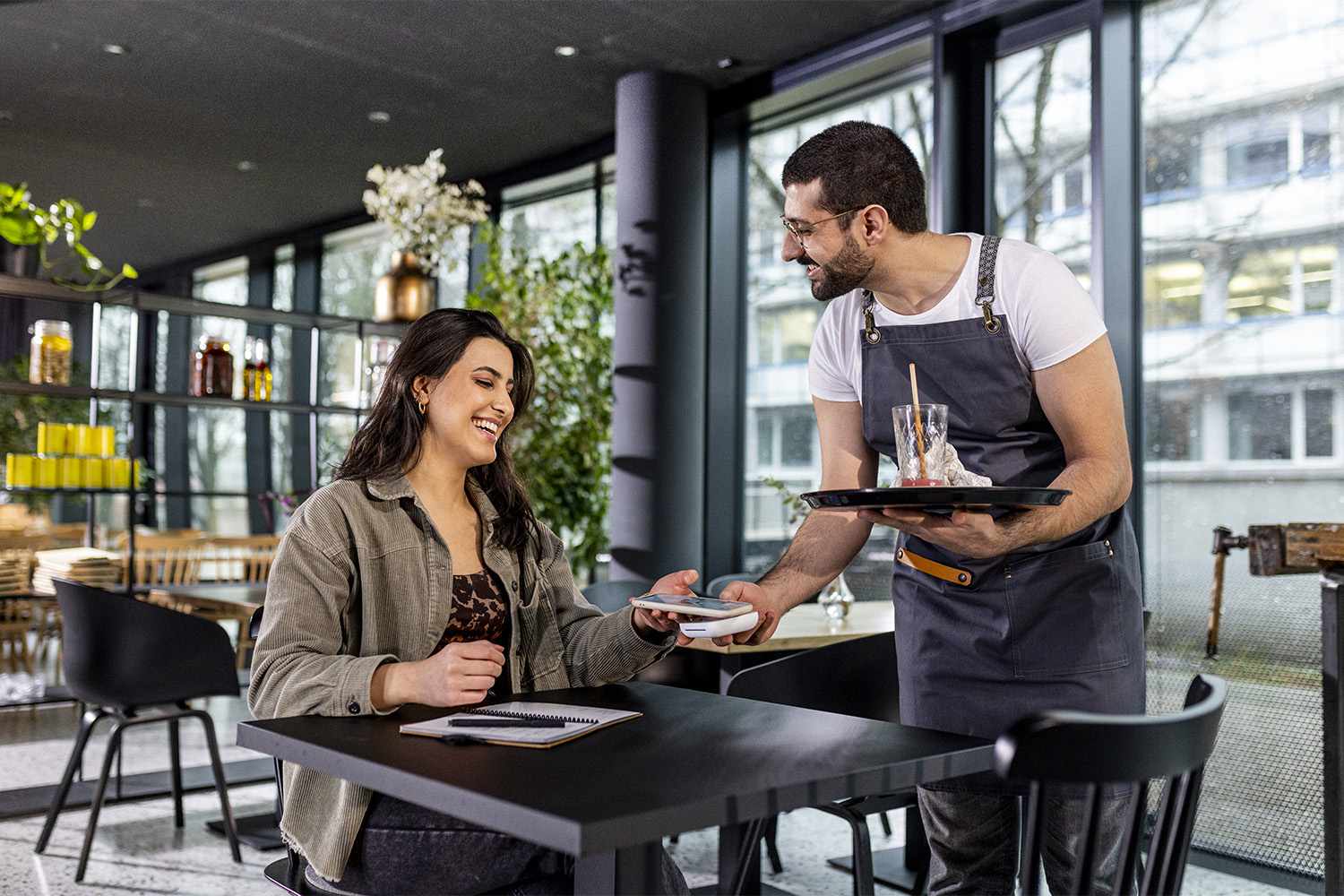 woman is paying with smartphone in a restaurant