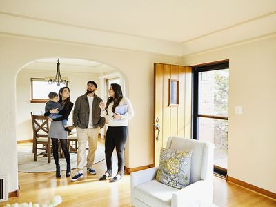 Wide shot of family looking at home for sale with real estate agent