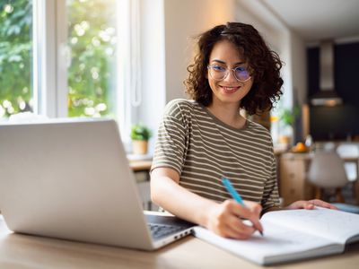 A worker at a computer with a notebook and pen