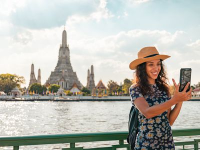 Woman smiling into phone in front of temple in Bangkok