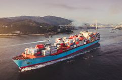 Aerial View of Container Ship Transporting Goods Sailing Across Ocean Leaving the Port