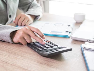 A businessman analyzing documents using his calculator.