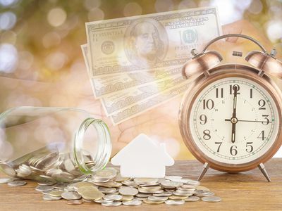 Currency beside alarm clock and hands at table