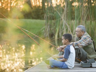 Grandfather and grandson fishing on a pier in the woods