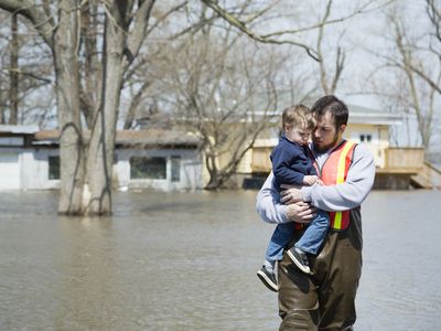 A man wades through flood waters holding his son in his arrms